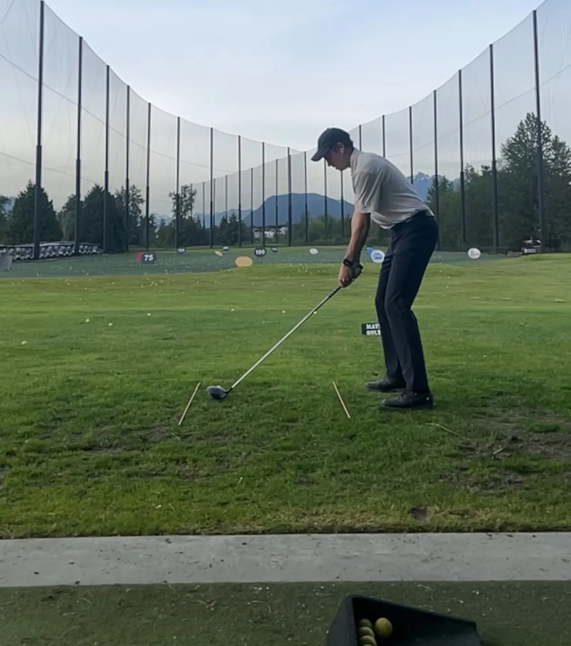 A golfer practising on a driving range.
