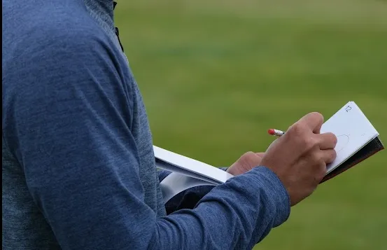 A golfer writing notes in a notebook.